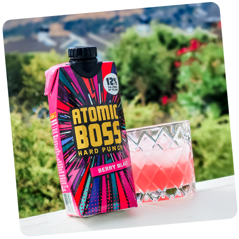 Tilted image of Berry Blast product with glass filled with product plus ice with greenery background